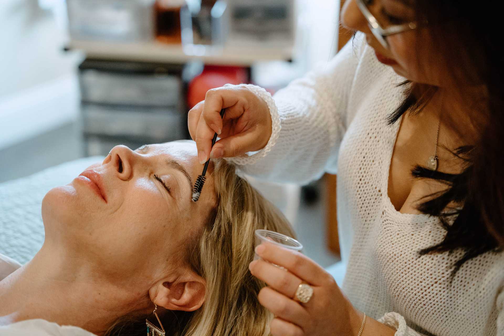 Woman receiving eyebrow grooming treatment at a salon.