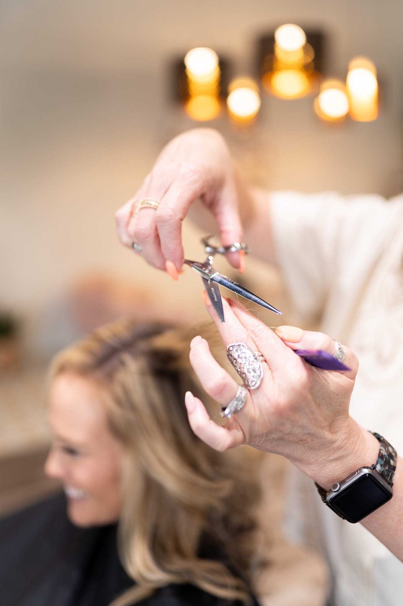 Haircut in progress at a salon, stylist using scissors on a client's hair.